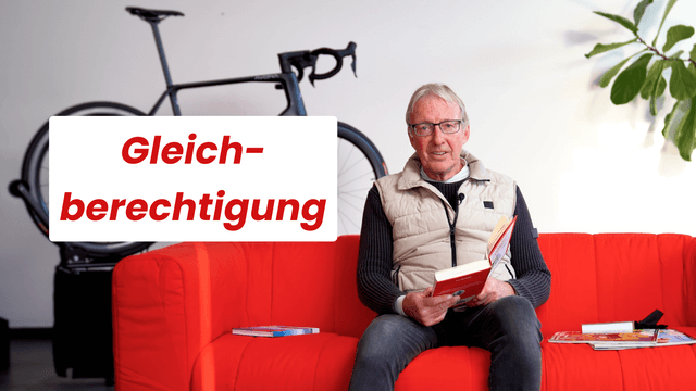 Mann sitzt auf rotem Sofa, liest ein Buch. Neben ihm ein Fahrrad. Text "Gleichberechtigung" im Bild. Pflanzen im Hintergrund.