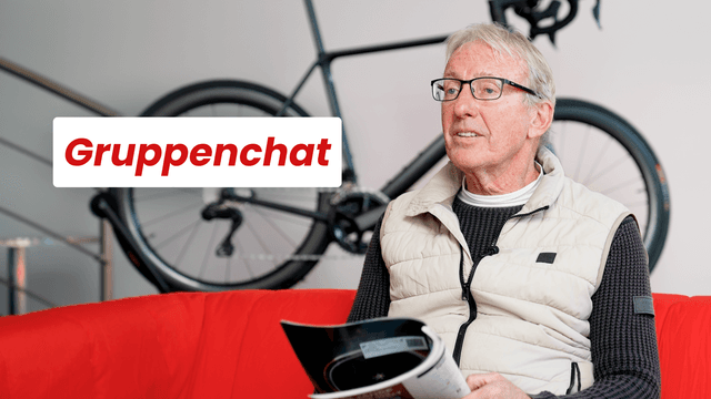 Ein Mann mit Brille und Weste sitzt auf einem roten Sofa und liest eine Zeitschrift. Im Hintergrund ist ein Fahrrad zu sehen. Text: "Gruppenchat".